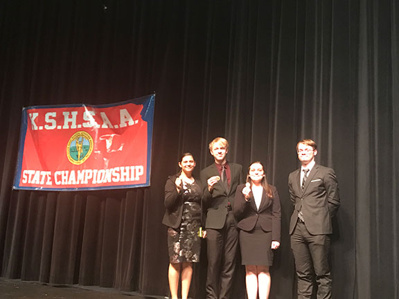 Jayln Lear, Patrick Heath, Bayle Sandy and Geoffrey Pafford on stage at Valley Center High School beside the KSHSAA banner where they received their state medals Saturday night.  The team placed 10th out of 27 5A schools.